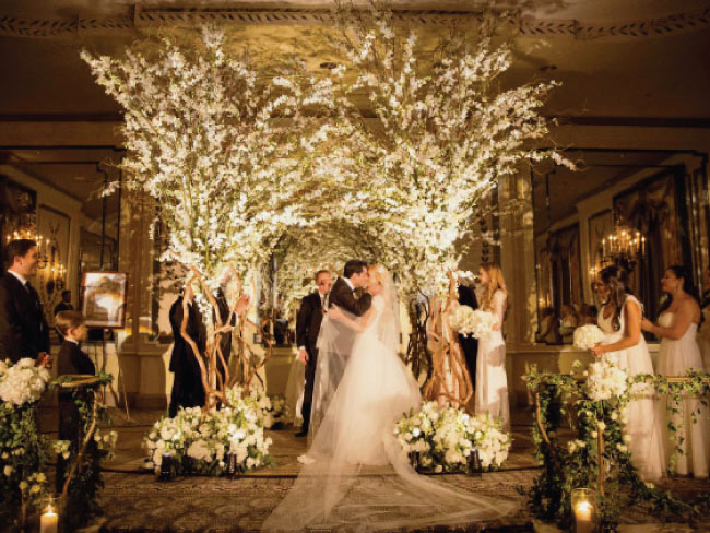 Romantic wedding scene with café lights and trees illuminated by uplighting in Charleston.
