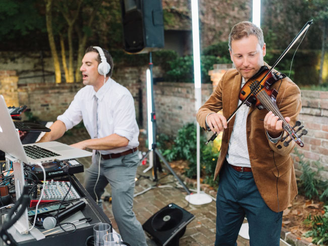 DJ with electric violinist performing live instrumentation at a Charleston event.