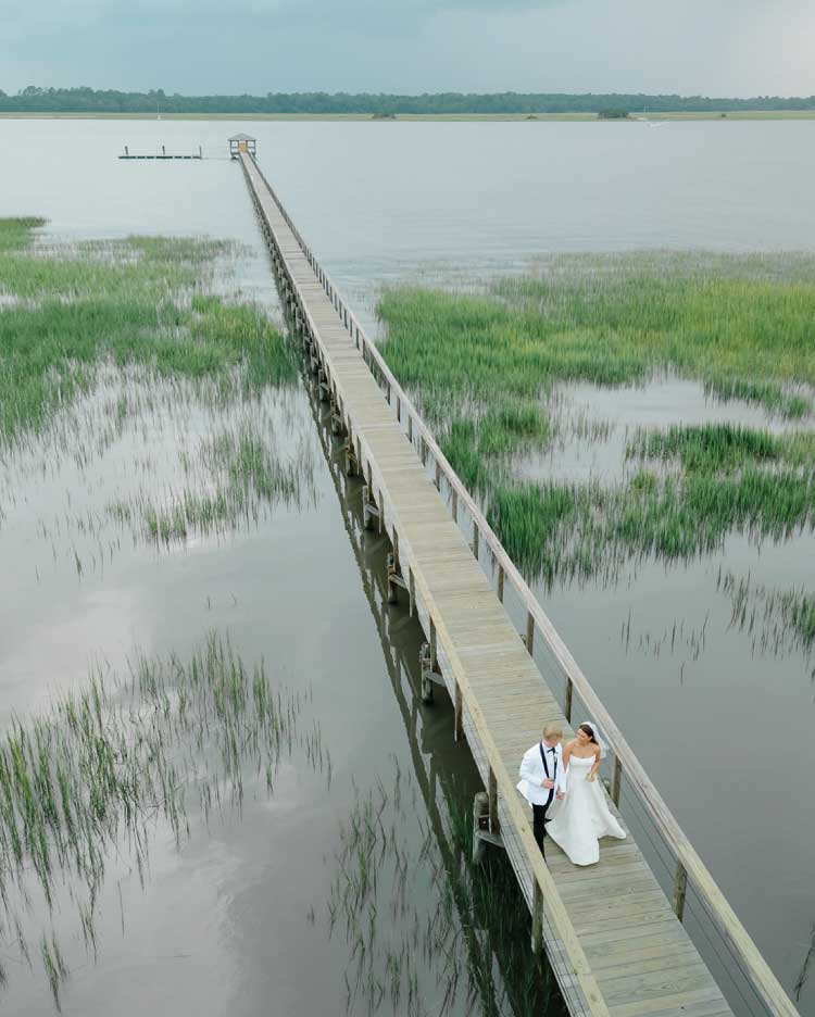 Charleston wedding couple walking along a Lowcountry marsh boardwalk at sunset